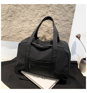Detail view of large black waterproof nylon tote bag with reinforced handles and front pocket