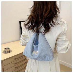 Détail du sac cabas plissé bleu clair avec papillon argenté et bandoulière chaîne