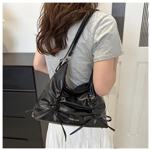 Detail of pleated black tote bag with bow accents and silver chain shoulder strap