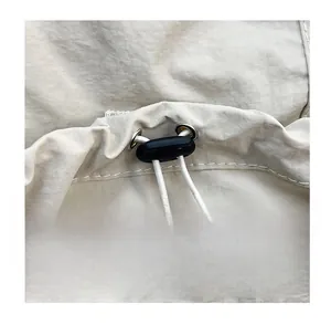 Detail of white fabric texture with a functional drawstring and black spring toggle stopper