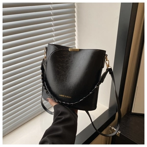 Detail of black vintage bucket bag featuring textured leather and gold metal buckle