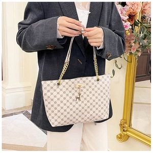 Detail of vintage beige tote bag with brown lattice pattern and golden deer charm