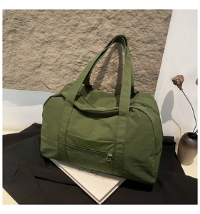 Detail of olive green nylon travel tote with wide straps and smooth front zipper pocket