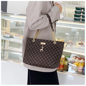 Brown tote bag with gold star pattern, deer charm, and chain strap shown on shoulder