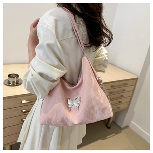Détail du sac à bandoulière rose plissé avec une boucle décorative en métal argenté papillon