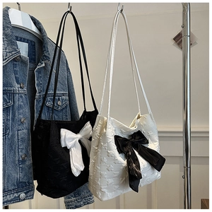 Detail of star-quilted shoulder bags in black and white with large contrast bows