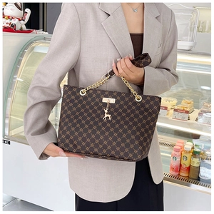 Close-up of vintage brown tote bag with classic monogram pattern and gold chain strap