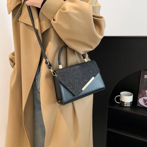Chic black flap handbag with glitter panel and golden metal trim on modern handle
