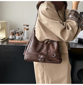 Detail of dark brown leather tote with vintage texture and triple silver buckle straps