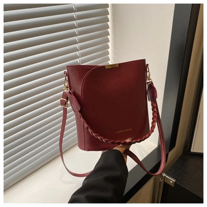 Macro detail of wine red bucket bag featuring woven handle and gold-tone metal hardware