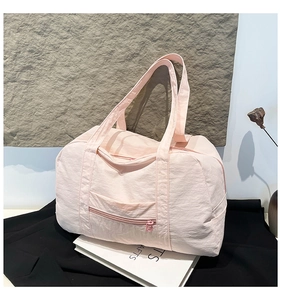 Detail of light pink nylon tote bag showing durable pleated fabric and front zip pocket