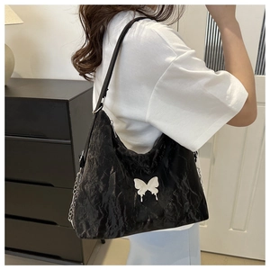 Détail du sac cabas noir brillant avec papillon blanc et bandoulière chaîne argent