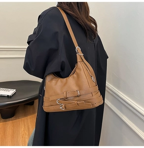 Detailed side view of caramel half-moon tote with multi-buckle straps and silver hardware