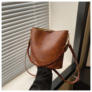 Detail of vintage brown bucket bag featuring woven handle and gold brand logo