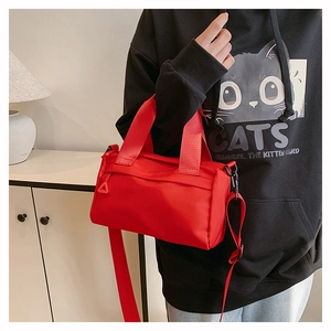 Detailansicht der roten Nylon-Zylindertasche mit breitem Gurtbandgriff und Schultergurt