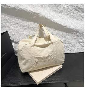 Close-up of beige waterproof nylon tote with crinkled texture and front zipper pocket