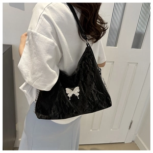 Détail du sac à bandoulière noir plissé avec boucle papillon argentée et bandoulière chaîne