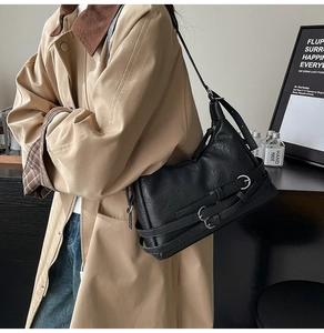 Detail of vintage black textured leather shoulder bag with triple decorative buckles