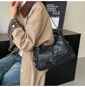 Detail of black pleated leather tote with parallel straps and silver metal buckles