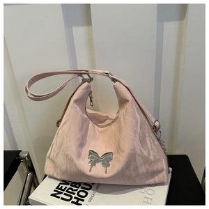 Détail du sac cabas rose clair avec pendentif papillon en métal argenté et surface texturée