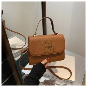 Détail du sac marron à motif litchi avec logo SM métallique et poignée supérieure robuste
