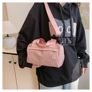 Detailansicht der pinkfarbenen Zylindertasche aus Nylon mit breitem Schultergurt