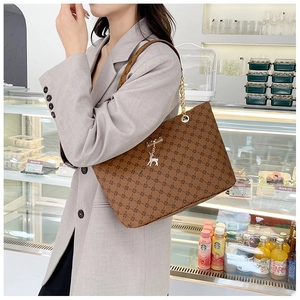 Close-up of brown patterned tote bag with gold chain strap and silver deer charm detail