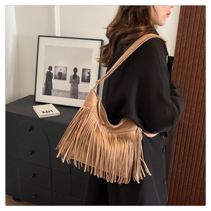 Detail of camel suede shoulder bag with long fringes and half-moon bohemian style design