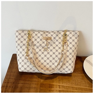 Detail of monogram tote bag with gold chain strap and decorative golden elk pendant