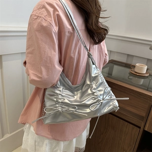 Silver metallic hobo tote bag with pleated design and bow accents shown on model