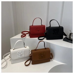 Gros plan sur la texture du cuir et le logo SM en métal des sacs à bandoulière
