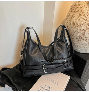 Close-up of black pleated leather tote with silver buckle and belt strap details