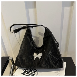Gros plan d'un sac à bandoulière plissé noir avec un grand fermoir papillon argenté