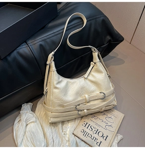 Detail of cream pleated leather tote with multiple silver buckles and adjustable strap