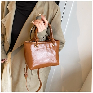 Détails de sac cabas en cuir verni marron avec nœuds et finitions dorées élégantes