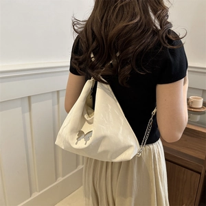 Sac fourre-tout chic en similicuir beige avec papillon et bandoulière porté par un mannequin