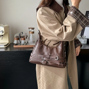 Vintage brown leather tote bag with decorative metal buckle straps and distressed texture