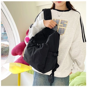 Detail of adjustable straps and drawstring closure on a minimalist black backpack