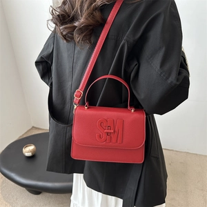 Sac à main minimaliste en cuir rouge avec gaufrage SM et bandoulière dans une pièce