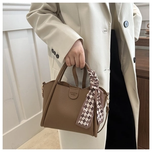 Sac seau marron chic avec texture litchi et ruban à carreaux sur un blazer beige