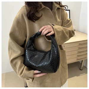 Detailed view of black woven leather texture on a minimalist hobo crescent bag