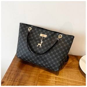 Close-up of black tote bag featuring grey geometric pattern and gold deer charm detail