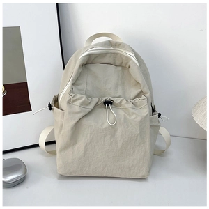 Detail of a beige minimalist backpack featuring a large main zipper and drawstring pocket