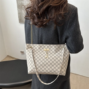 Chic beige tote bag with M-letter pattern and dual straps shown on a model's shoulder