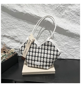 Detail of tweed checkered tote with V-shaped opening and white leather trim accents