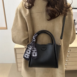 Sac seau minimaliste en cuir noir avec foulard en soie et finitions dorées élégantes
