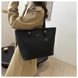 Detail view of black leather tote bag with gold lettering and adjustable buckle strap
