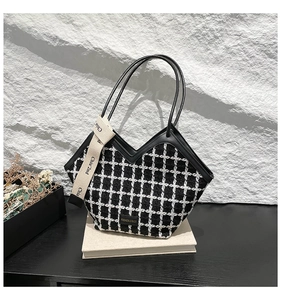 Detail of black and white tweed bucket bag featuring leather trim and fashion logo