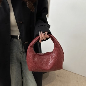 Minimalist deep red woven leather crescent hobo handbag for women held by model