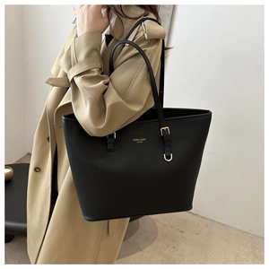 Detail of black leather tote bag with gold hardware and D-ring on khaki trench coat